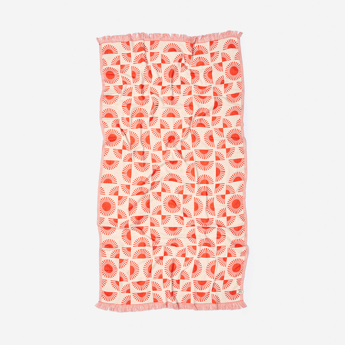 Turkish towel with red and white geometric sunburst pattern and fringe edges.