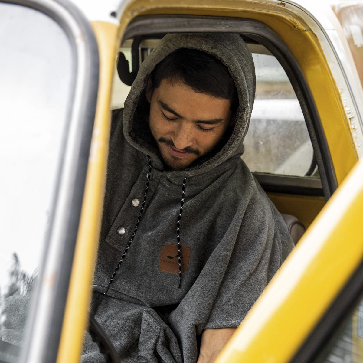 Gray towel poncho with hood displayed on car seat.