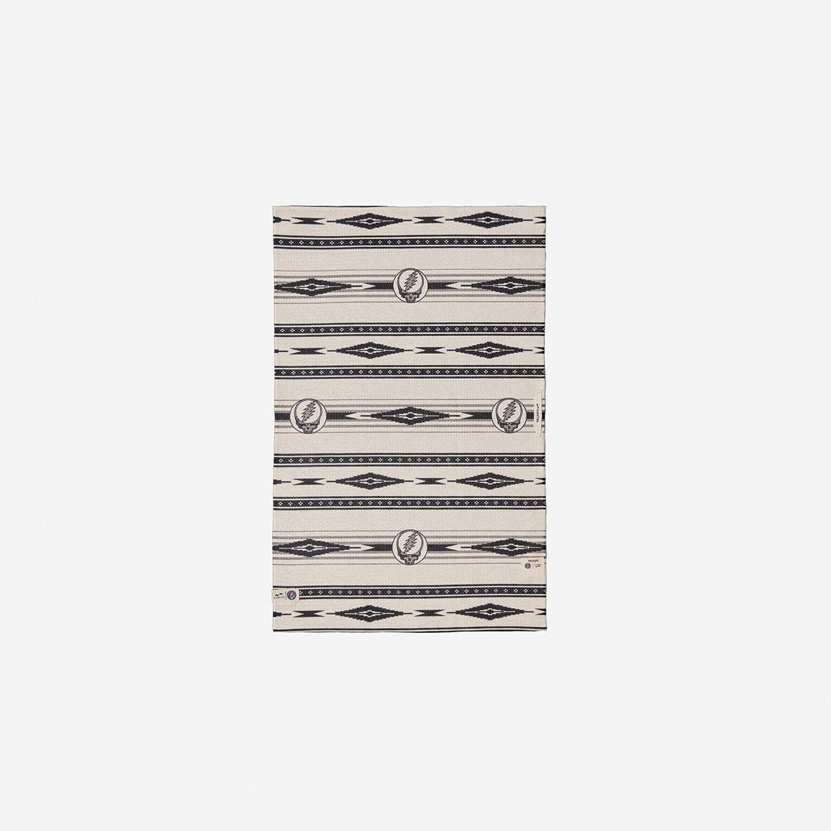 Beige blanket with vintage-style black and grey patterns on soft white fabric.