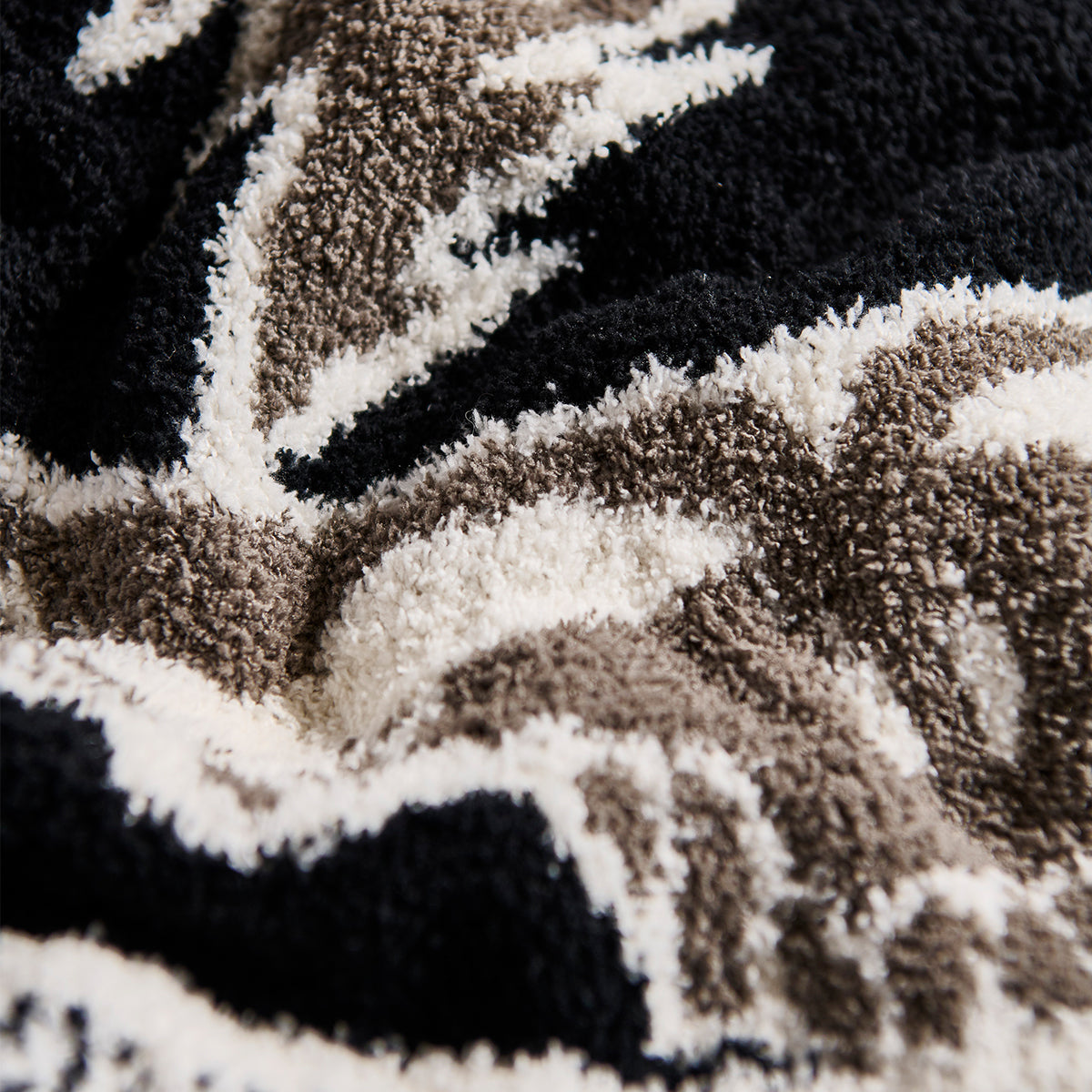 Woven blanket with black, white, and beige geometric patterns for home decor.
