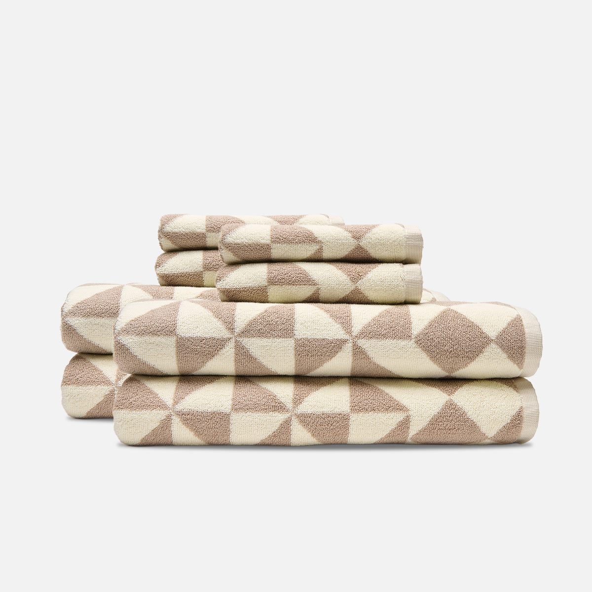 Cotton bath towels with beige and cream geometric patterns, stacked.