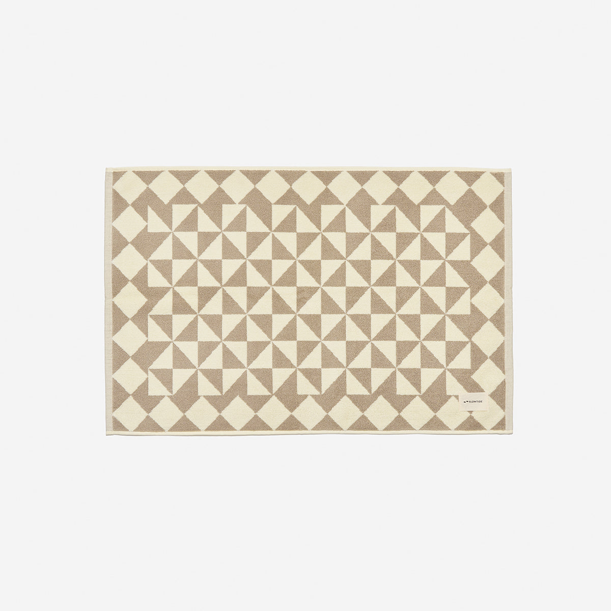 Cotton bath mat with beige and cream geometric triangle and diamond pattern.