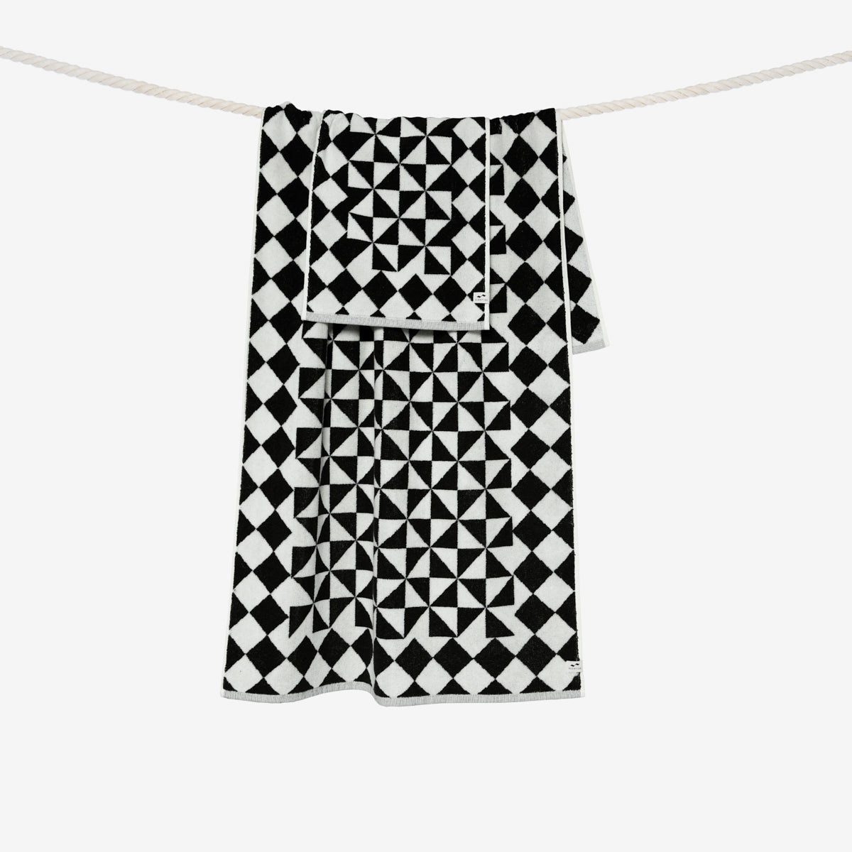 Black bath towel with geometric pattern on a clothesline.