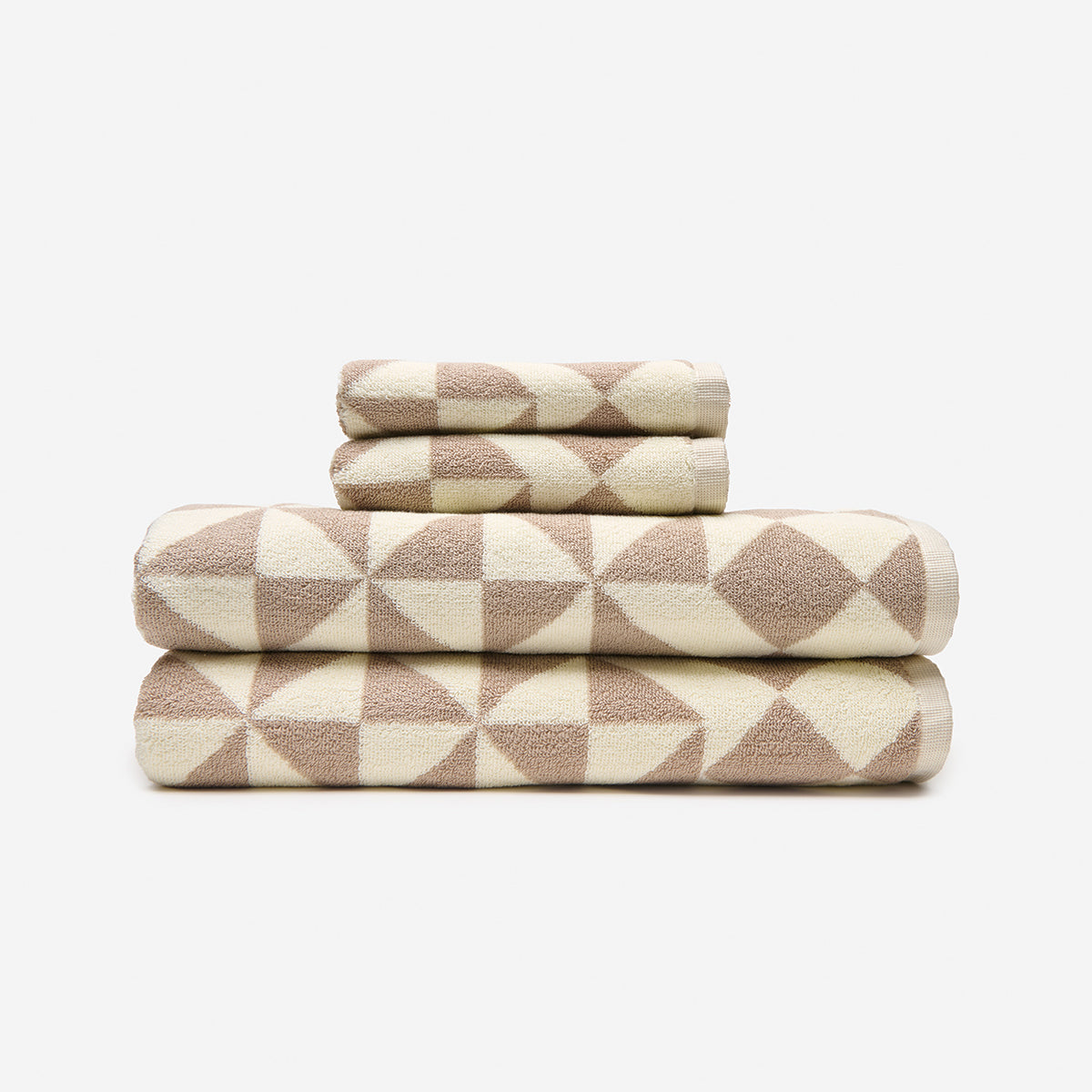 Cotton towels with beige and cream geometric triangle pattern, stacked.