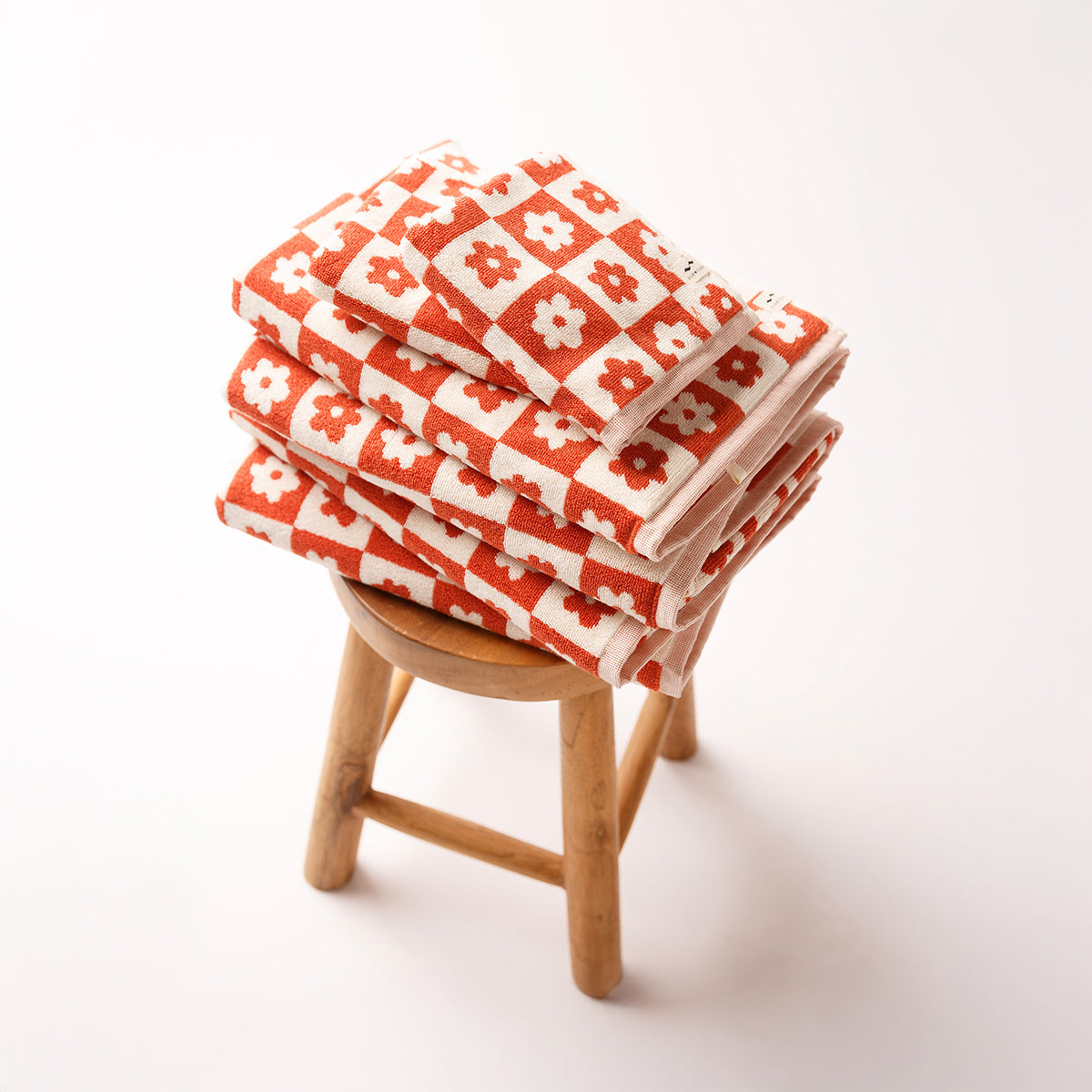 Cotton hand towels with floral geometric pattern on wooden stool.