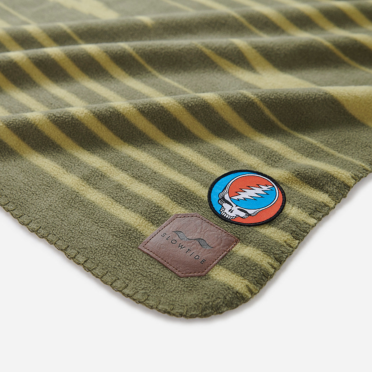Vintage throw blanket with green stripes and Steal Your Face patch.