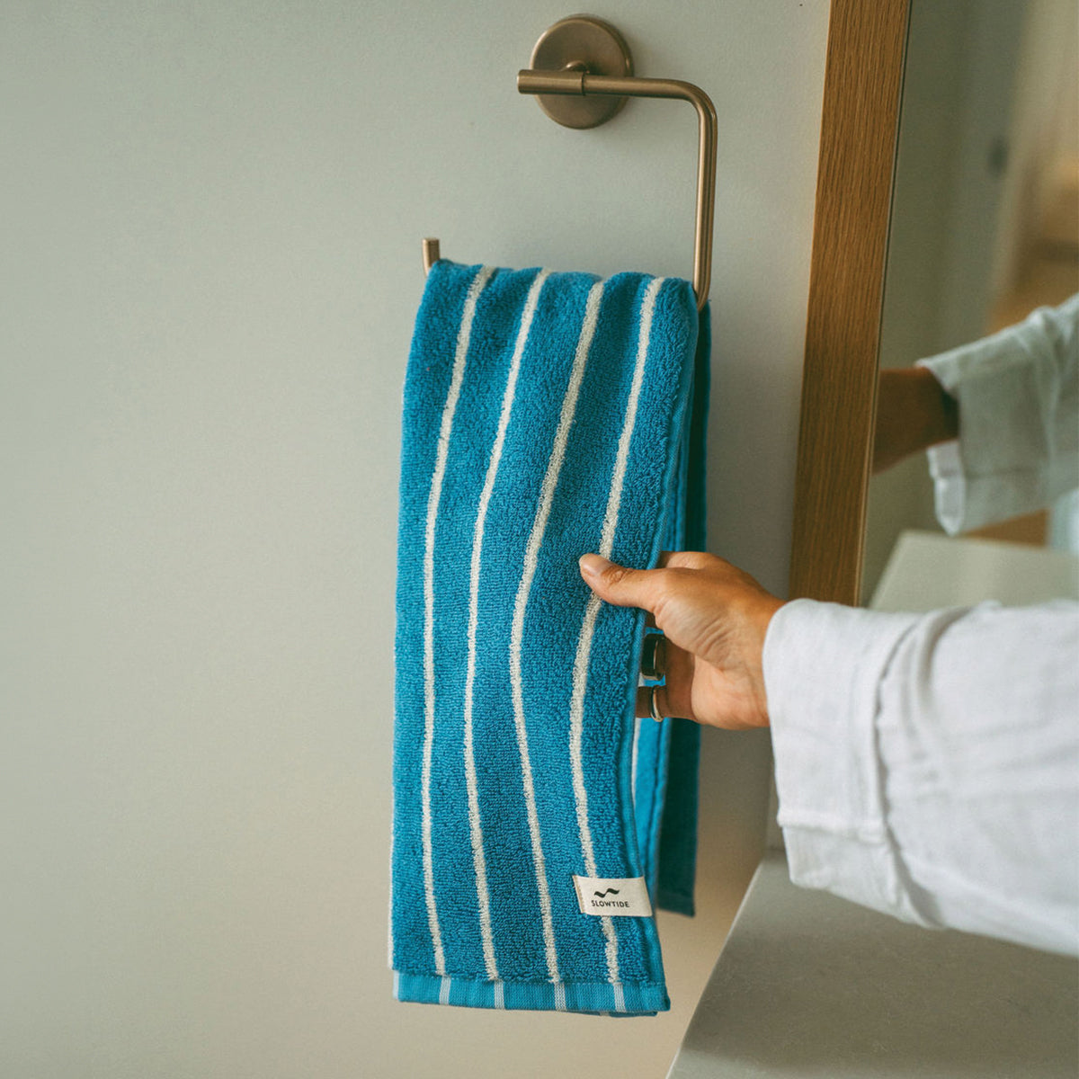 Cotton hand towel in blue and white stripes hanging on a rack.