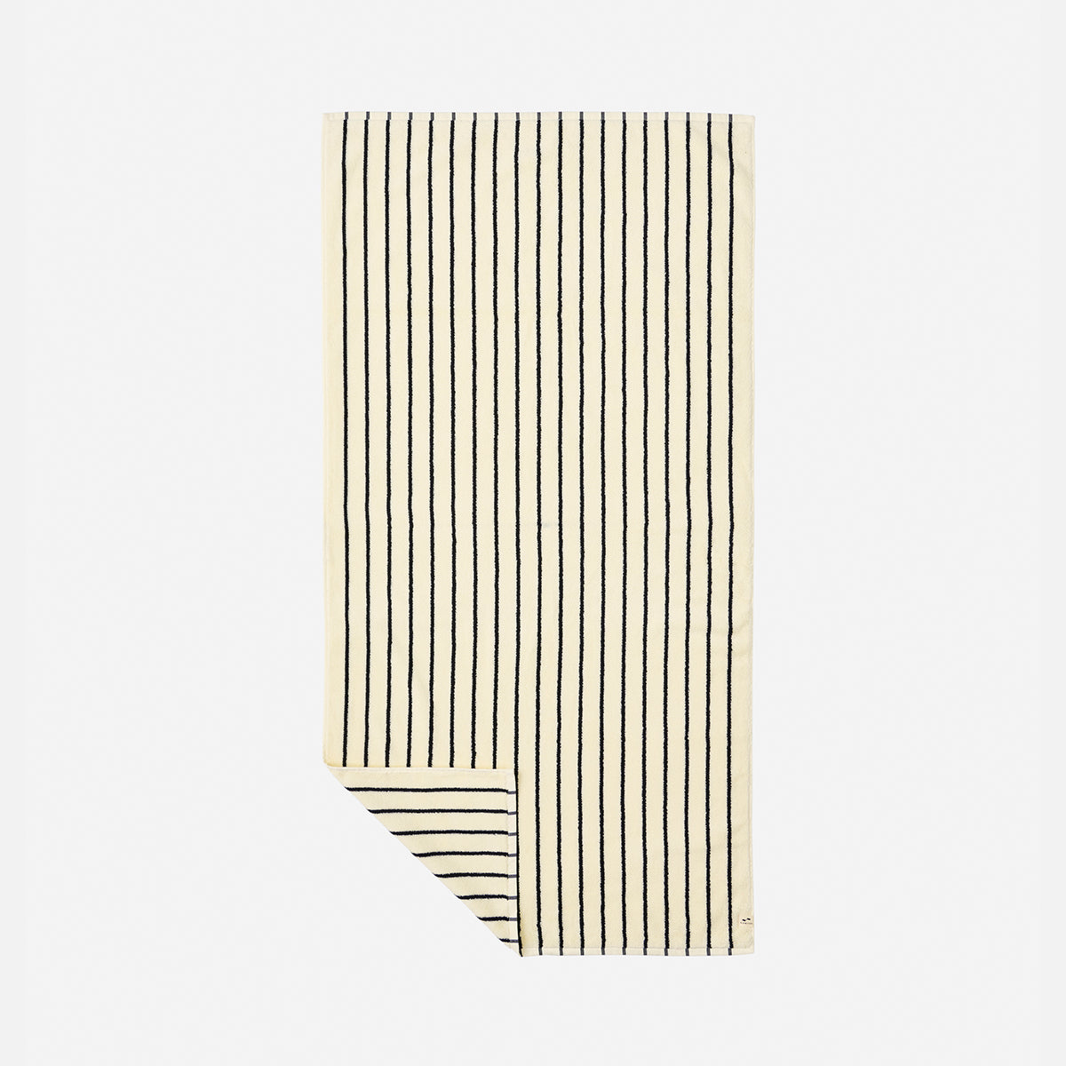 Cotton towel in cream with vertical black stripes and folded corner showing reverse side.