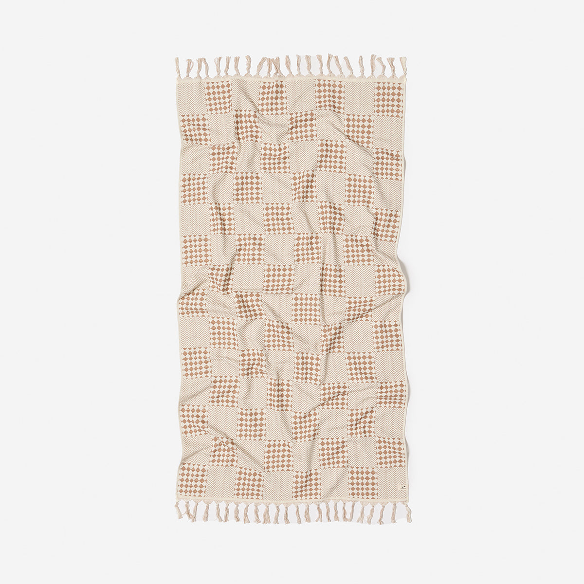 Checkered beige and brown sand resistant towel with fringed edges, flat on surface.