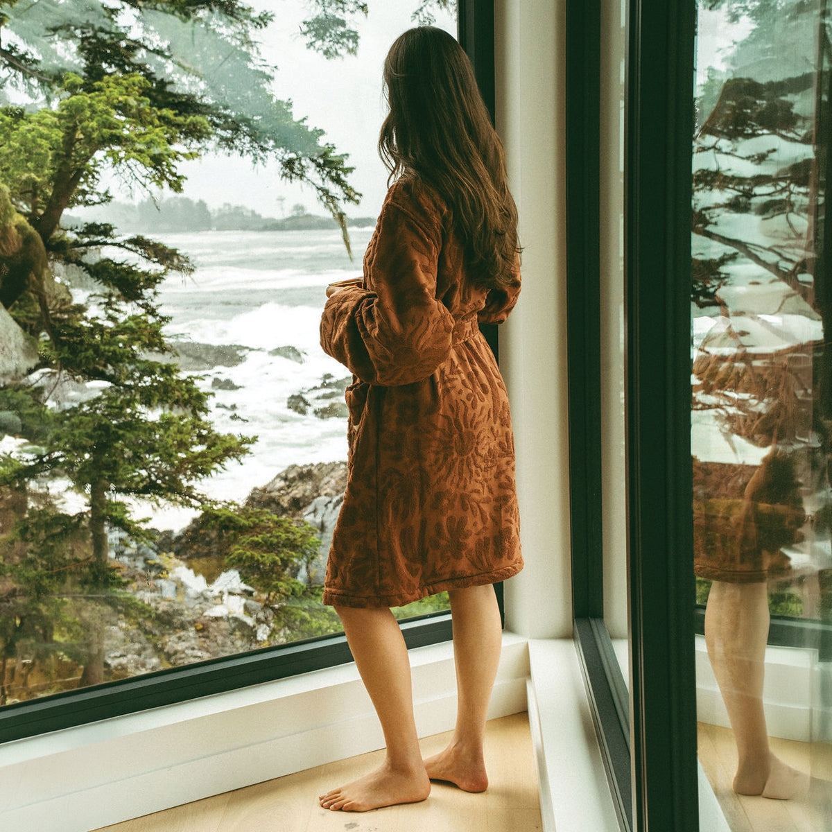 Brown embossed plush robe by an ocean-view window.