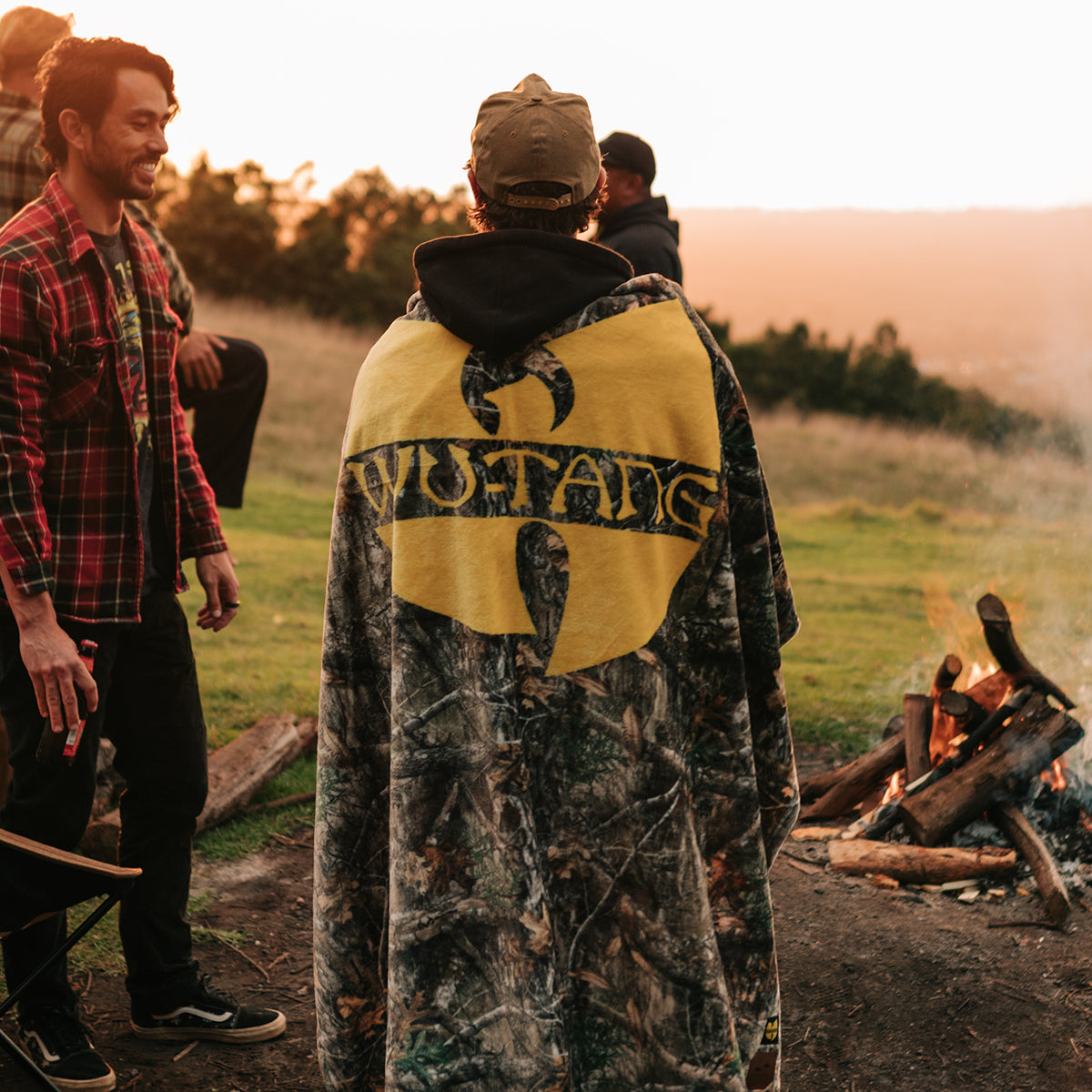 Fleece throw with bold graphic design, shown outdoors by a campfire at sunset.