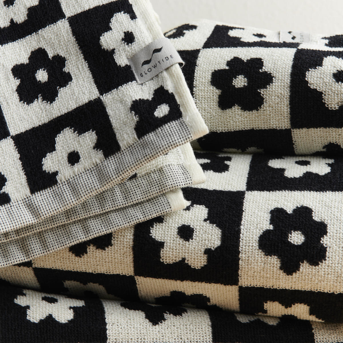Hand towels with black and white checkerboard and floral patterns, neatly folded.