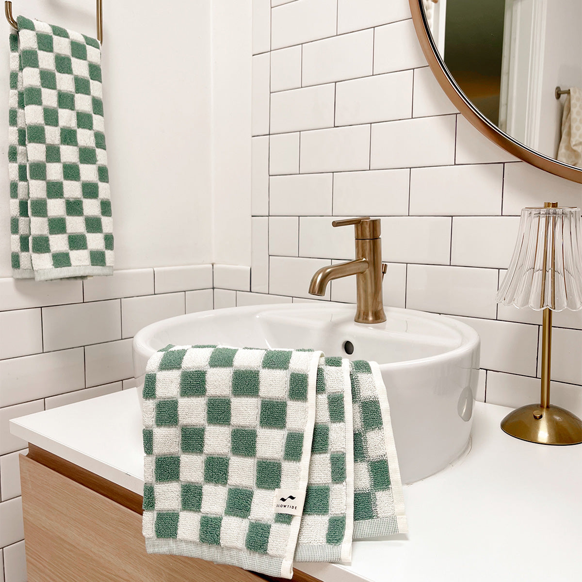 Hand towel with sage and white checkerboard weave, shown in a modern bathroom.