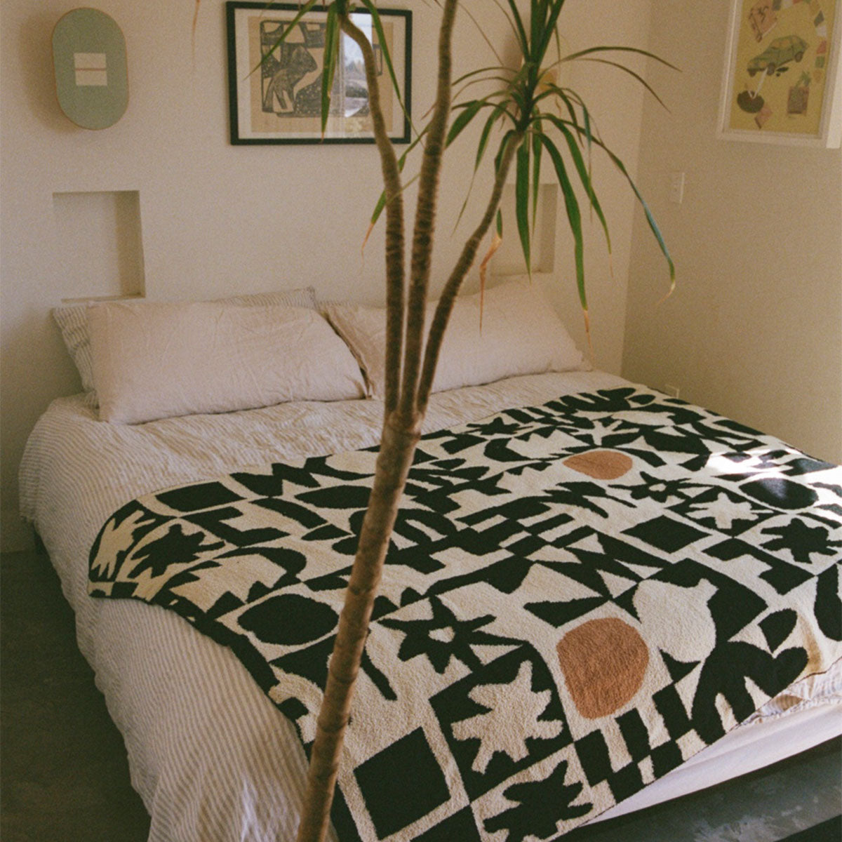 Bed with modern art patterned blanket in cozy setting.