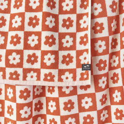 Hand towel in orange and white floral geometric pattern, sustainably sourced cotton, corner tag.