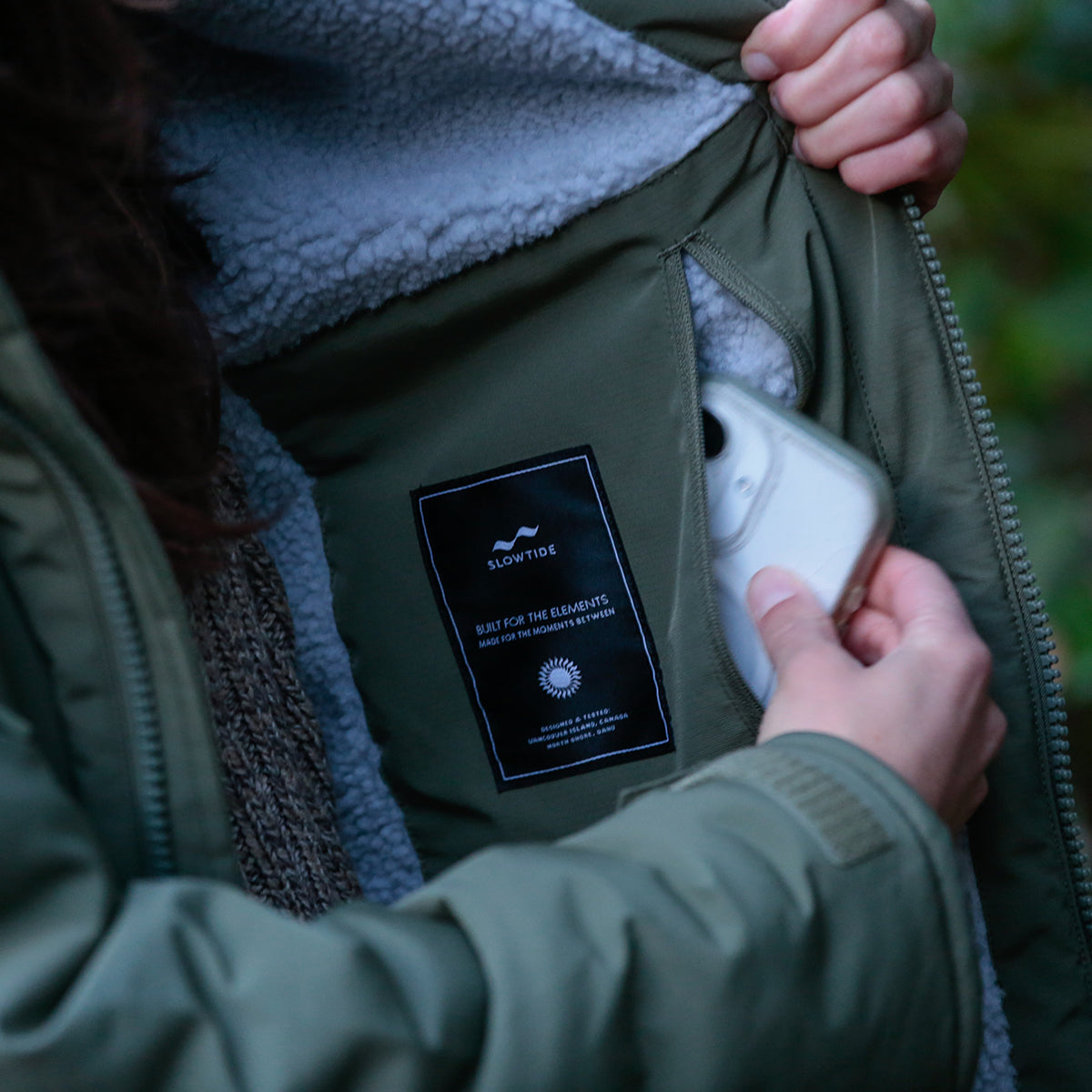 Green parka with fleece lining, white item in inner pocket.