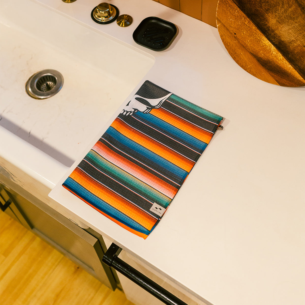 Vintage quick-dry kitchen towel on white counter near sink and soap dish.