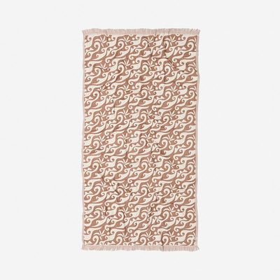 Beige cotton towel with white wave print and fringe on short edges.