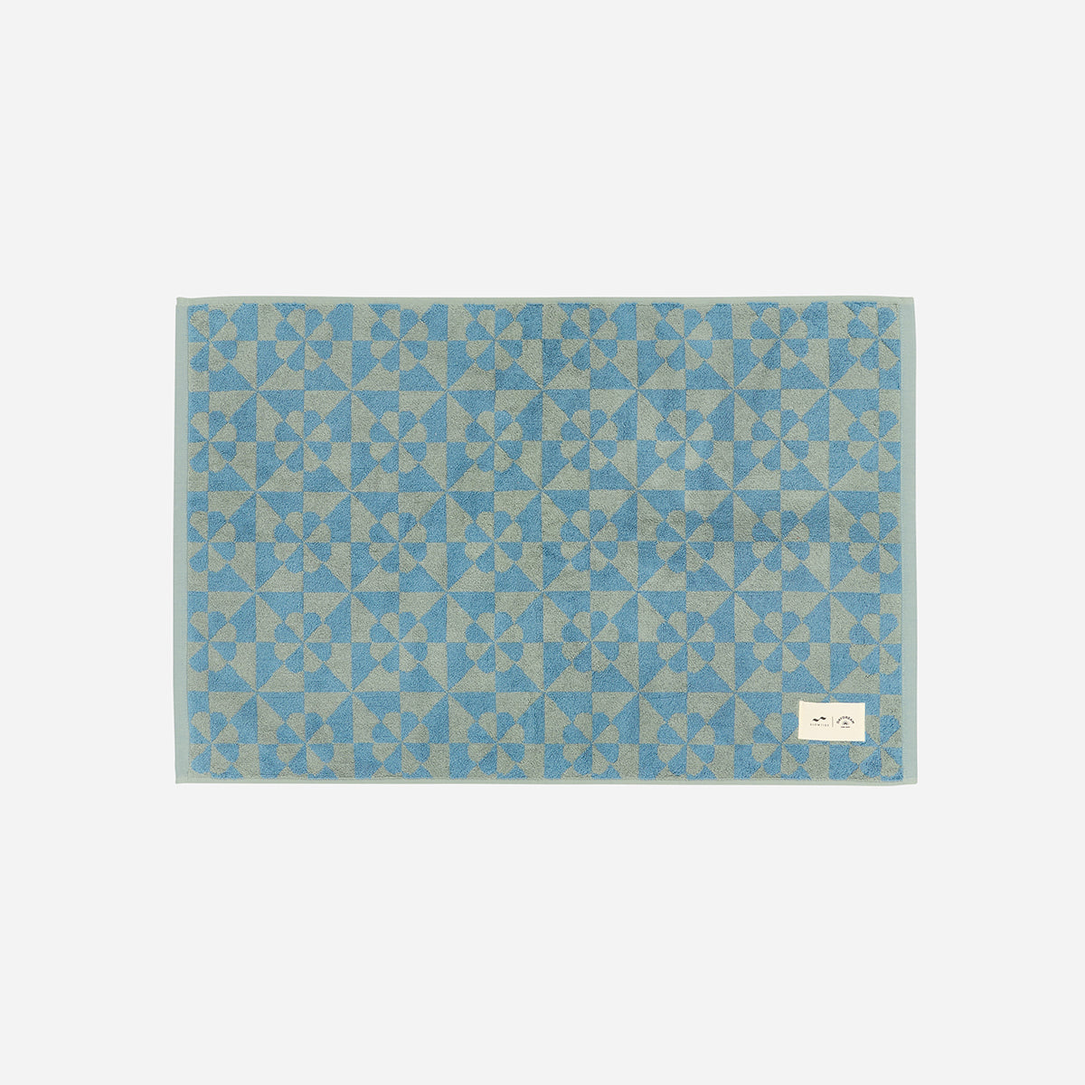 Sand resistant blue towel with geometric flower pattern on light gray background.