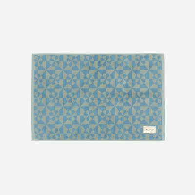 Sand resistant blue towel with geometric flower pattern on light gray background.