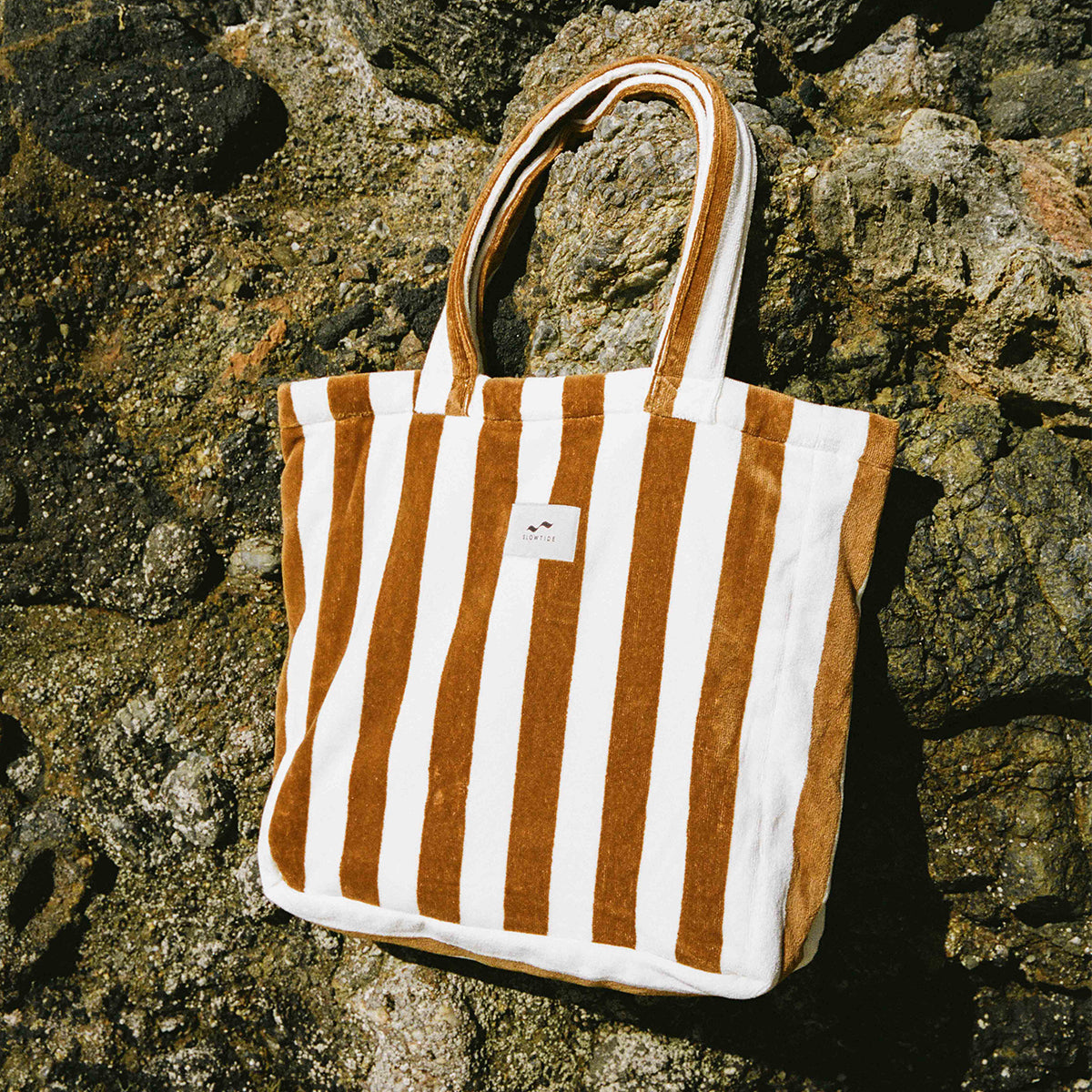 Tote bag with brown and white stripes on rocks.