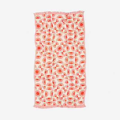 Turkish towel with red and white geometric sunburst pattern and fringe edges.
