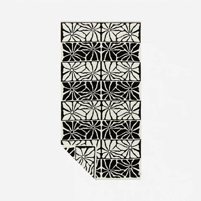 Patterned rug with black and white abstract floral design, sand-resistant style.