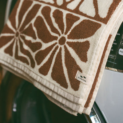 Bath towel with brown and white floral pattern draped on washing machine.