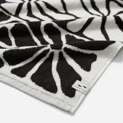 Bath towel with black and white abstract floral stripe pattern.