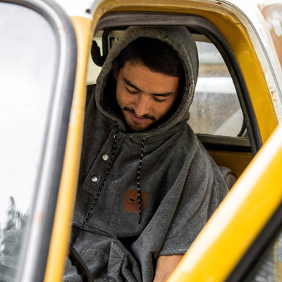 Gray towel poncho with hood displayed on car seat.