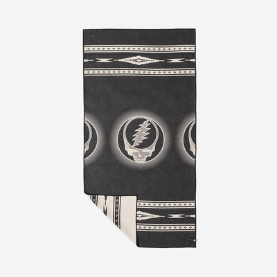Blanket, quick-drying fabric, black and white with skull and lightning bolt pattern, corner folded.
