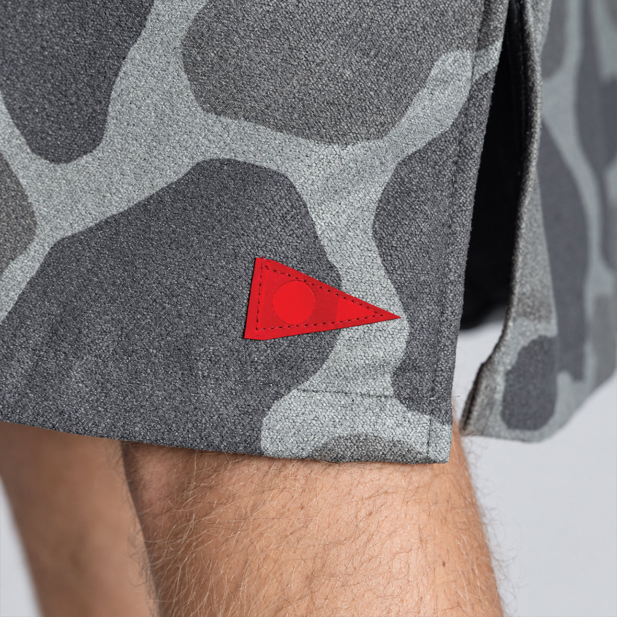 Gray camo shorts with red triangle patch near hem, quick-dry material.