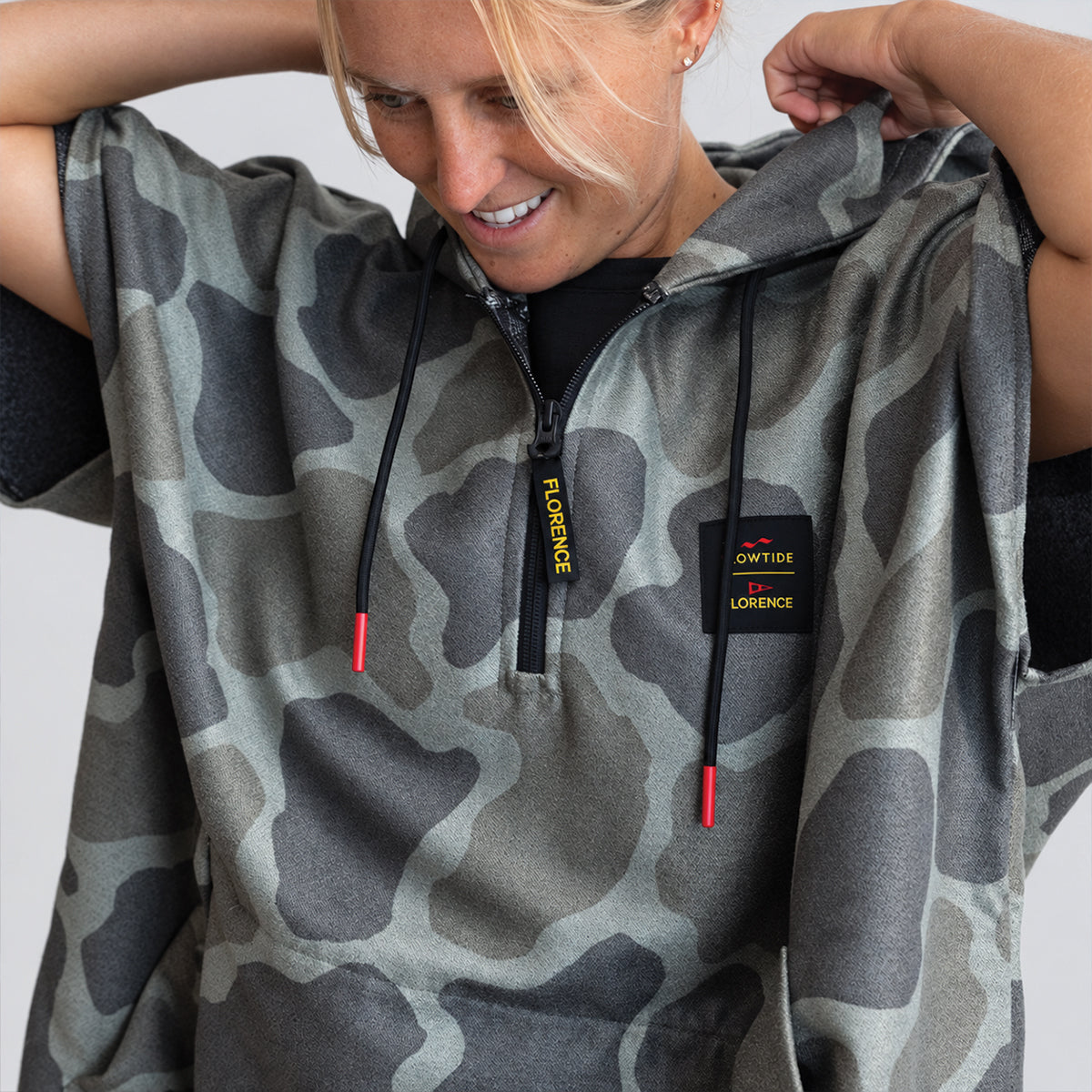 Surf changing poncho in gray camo with black drawstrings and yellow text, for beach use.