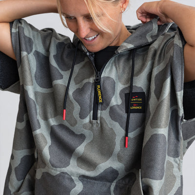 Surf changing poncho in gray camo with black drawstrings and yellow text, for beach use.