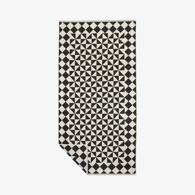 Black cotton bath towel with geometric pattern, 600 GSM, corner folded.