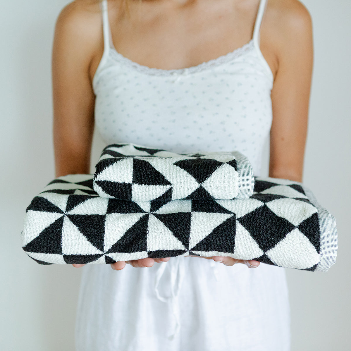 Black bath towels with geometric pattern, shown folded for display.