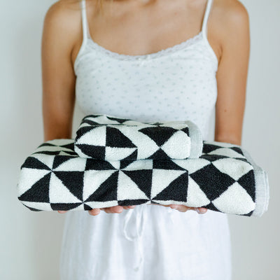Black bath towels with geometric pattern, shown folded for display.
