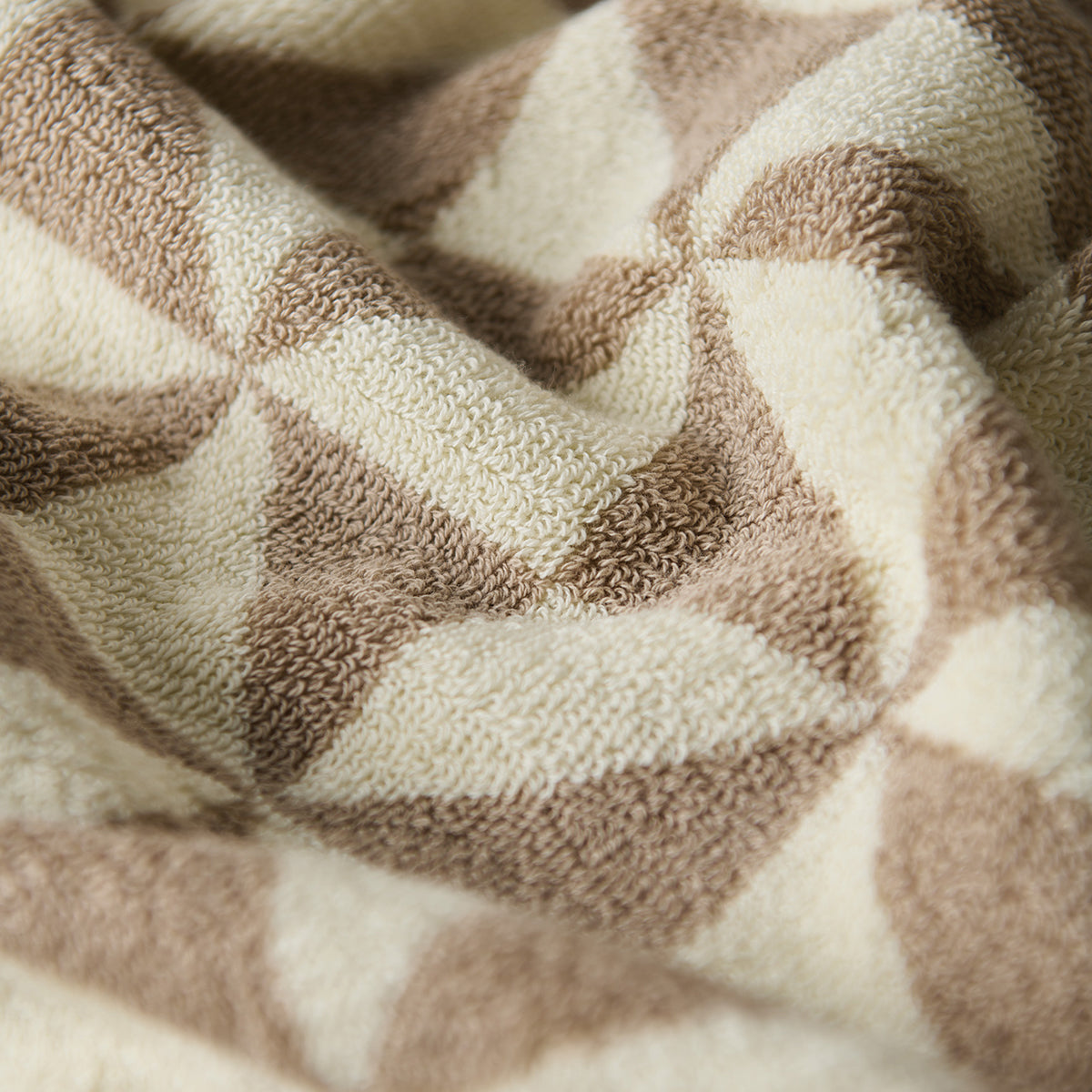 Bath towel with beige and cream geometric pattern.