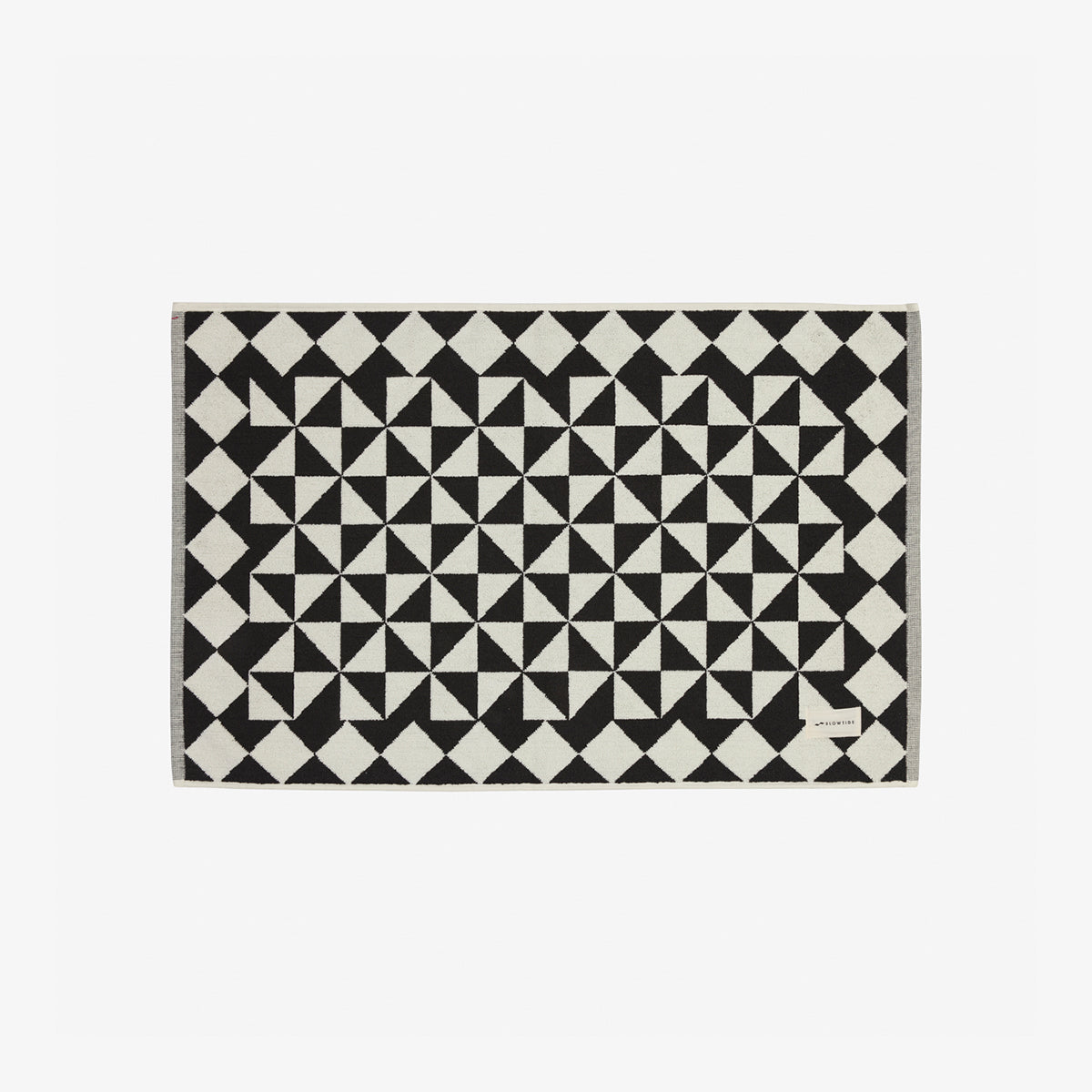 Cotton bath mat with black and white pinwheel geometric pattern, shown on a flat surface.