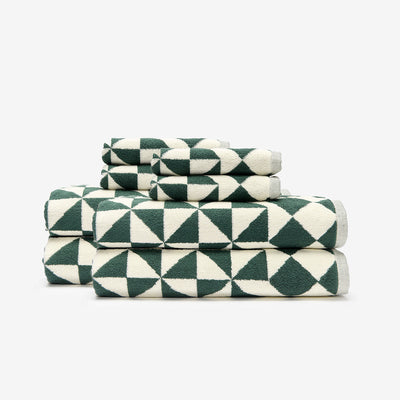 Bath towels with green and white geometric pattern stacked neatly.