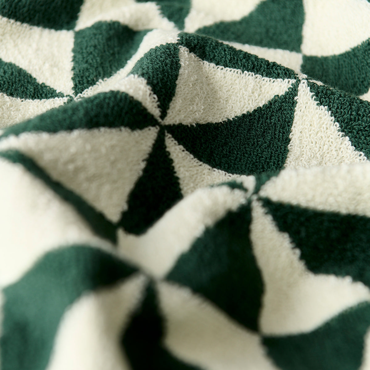 Cotton towel with green and white geometric pattern, close-up of fabric texture.