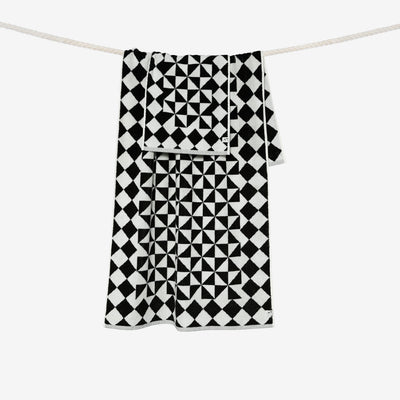 Black bath towel with geometric pattern on a clothesline.
