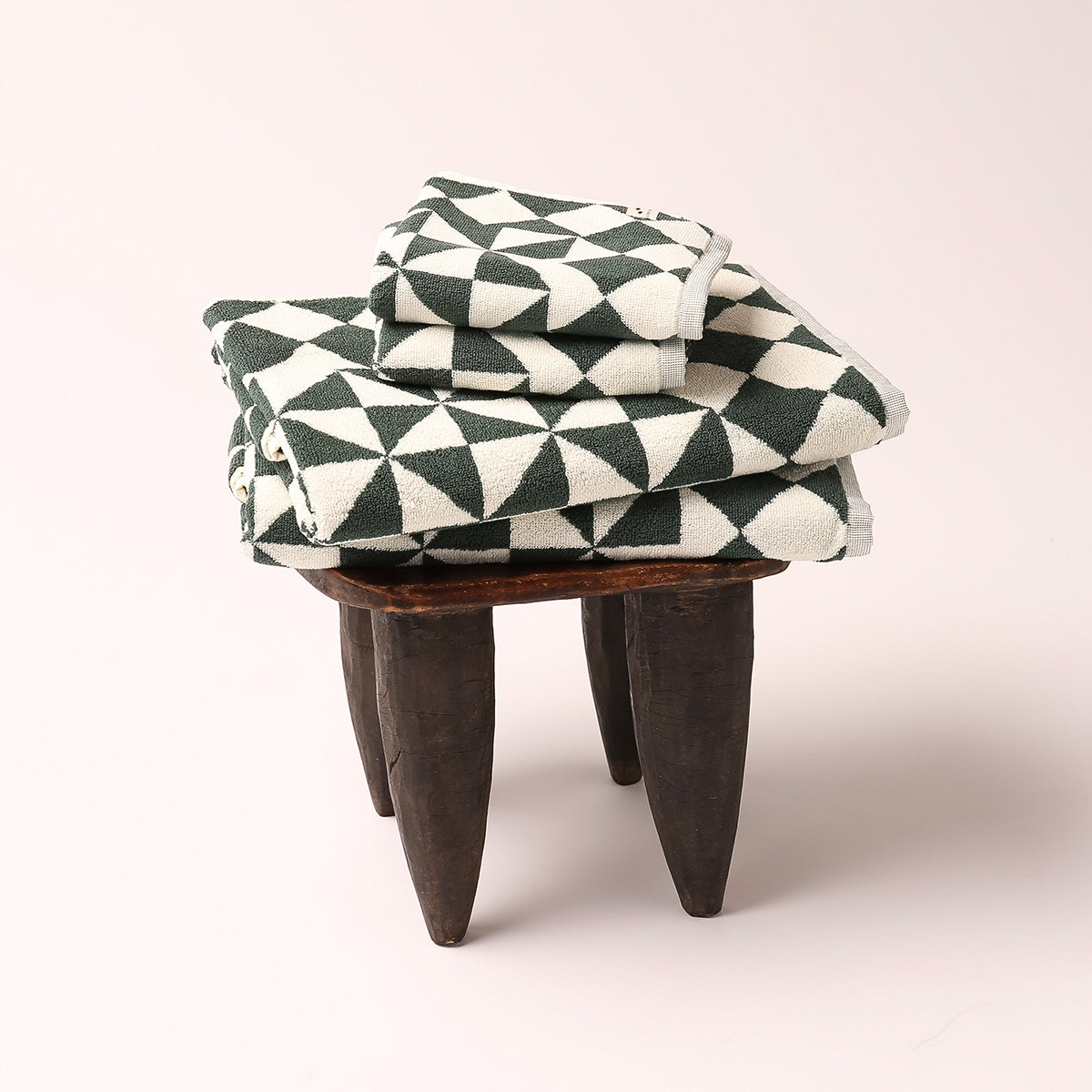 Hand towels with geometric pattern stacked on wooden stool.