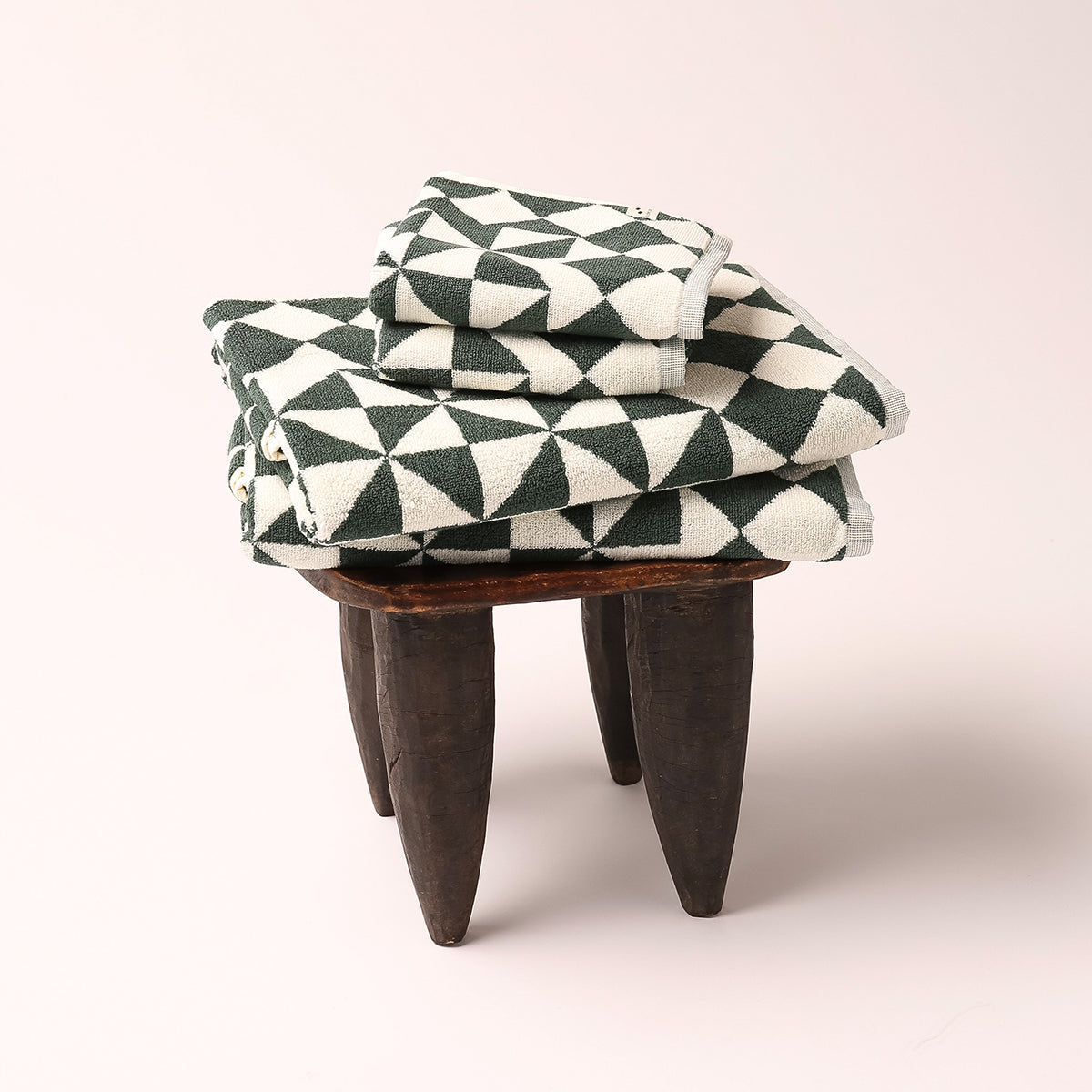 Hand towels with geometric pattern stacked on wooden stool.