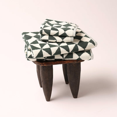 Hand towels with geometric pattern stacked on wooden stool.