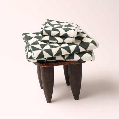 Hand towels with geometric pattern stacked on wooden stool.