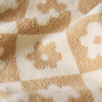 Cotton towel with floral checkerboard pattern, sustainably sourced.