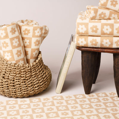 Cotton beige and white bath towels in a basket, on a stool, and laid out on the floor.