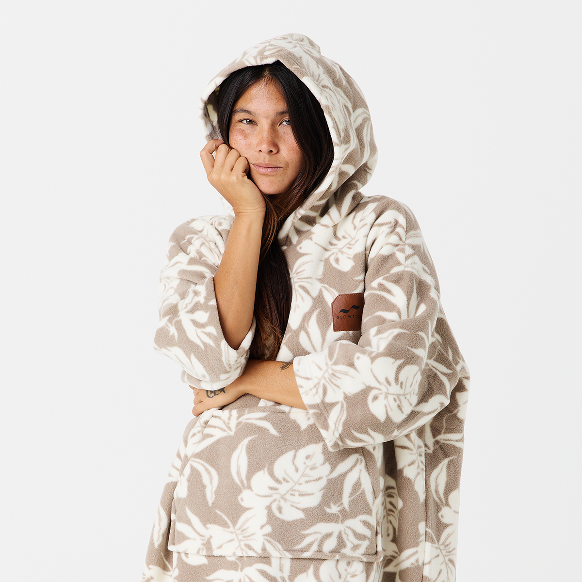 Hooded fleece poncho with beige and white tropical print pattern.