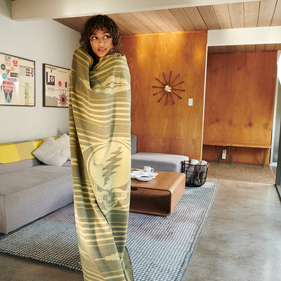 Throw blanket with colorful pattern draped over sofa in modern living room with wood accents.